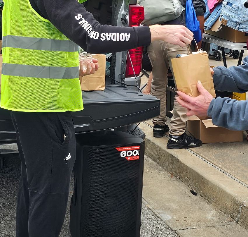 A volunteer hands a sack lunch to a guest